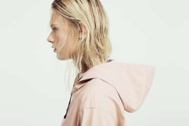 Profile of a woman with blonde hair and a pale pink coat