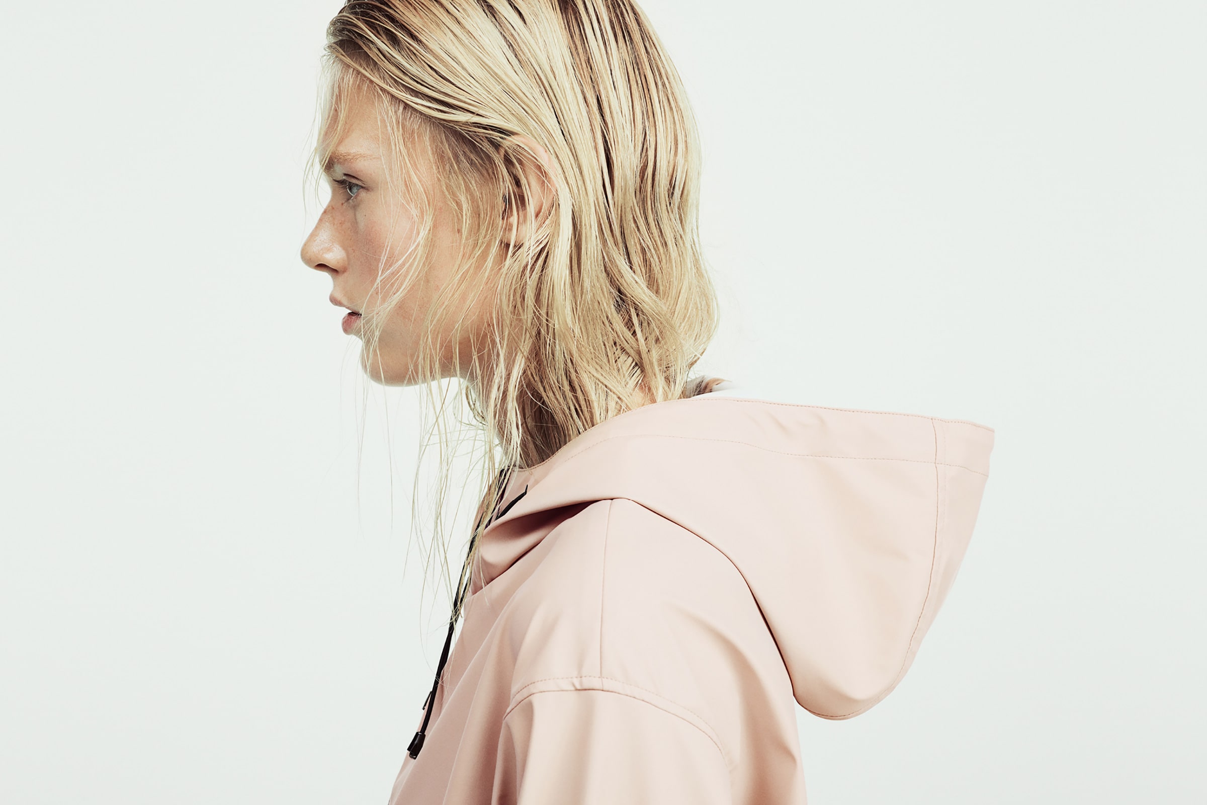 Profile of a woman with blonde hair and a pale pink coat