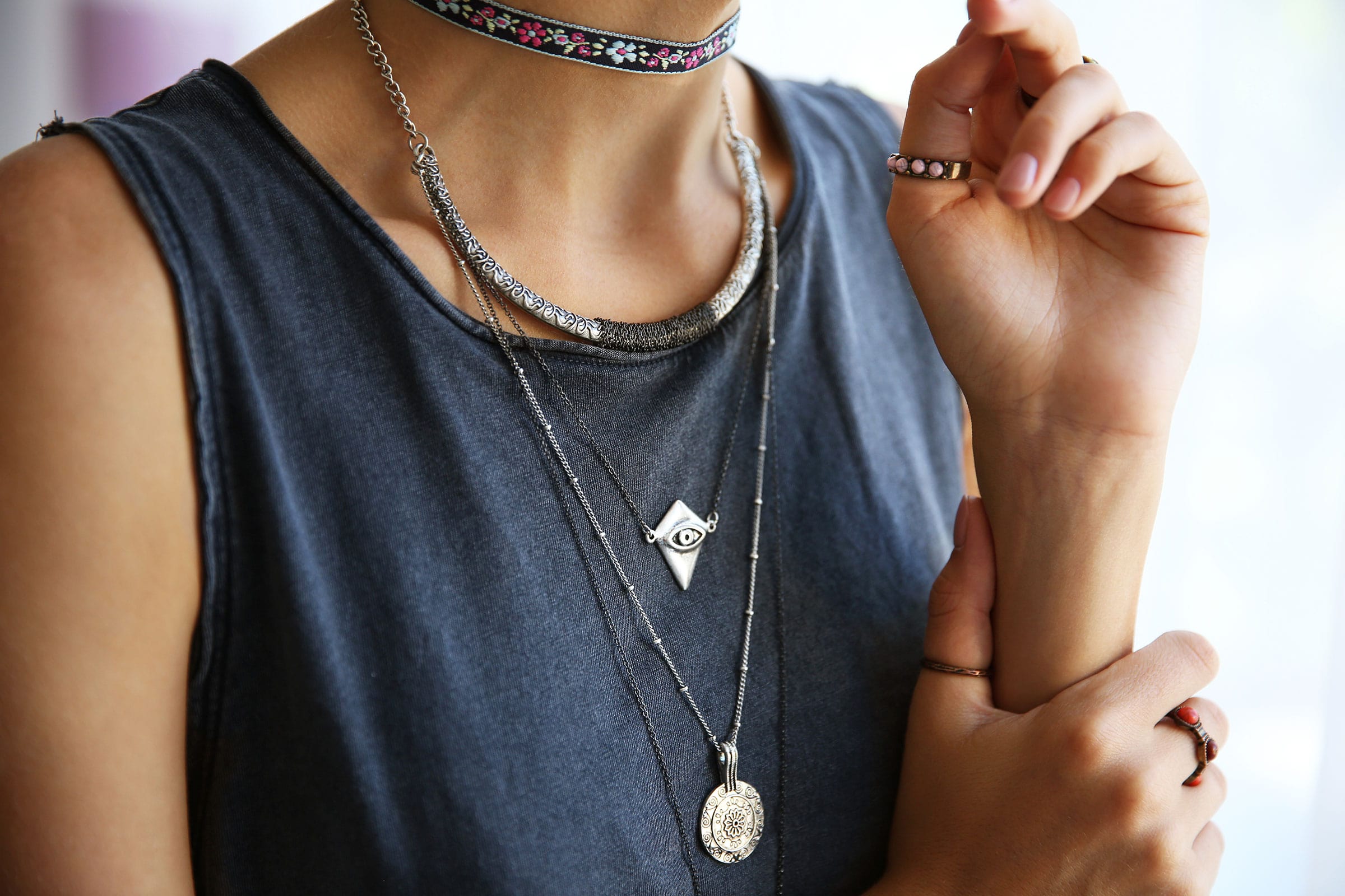 Layered silver necklaces over a dark sleeveless top