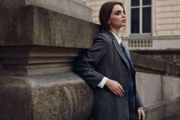 Woman in a tailored coat beside a stone building