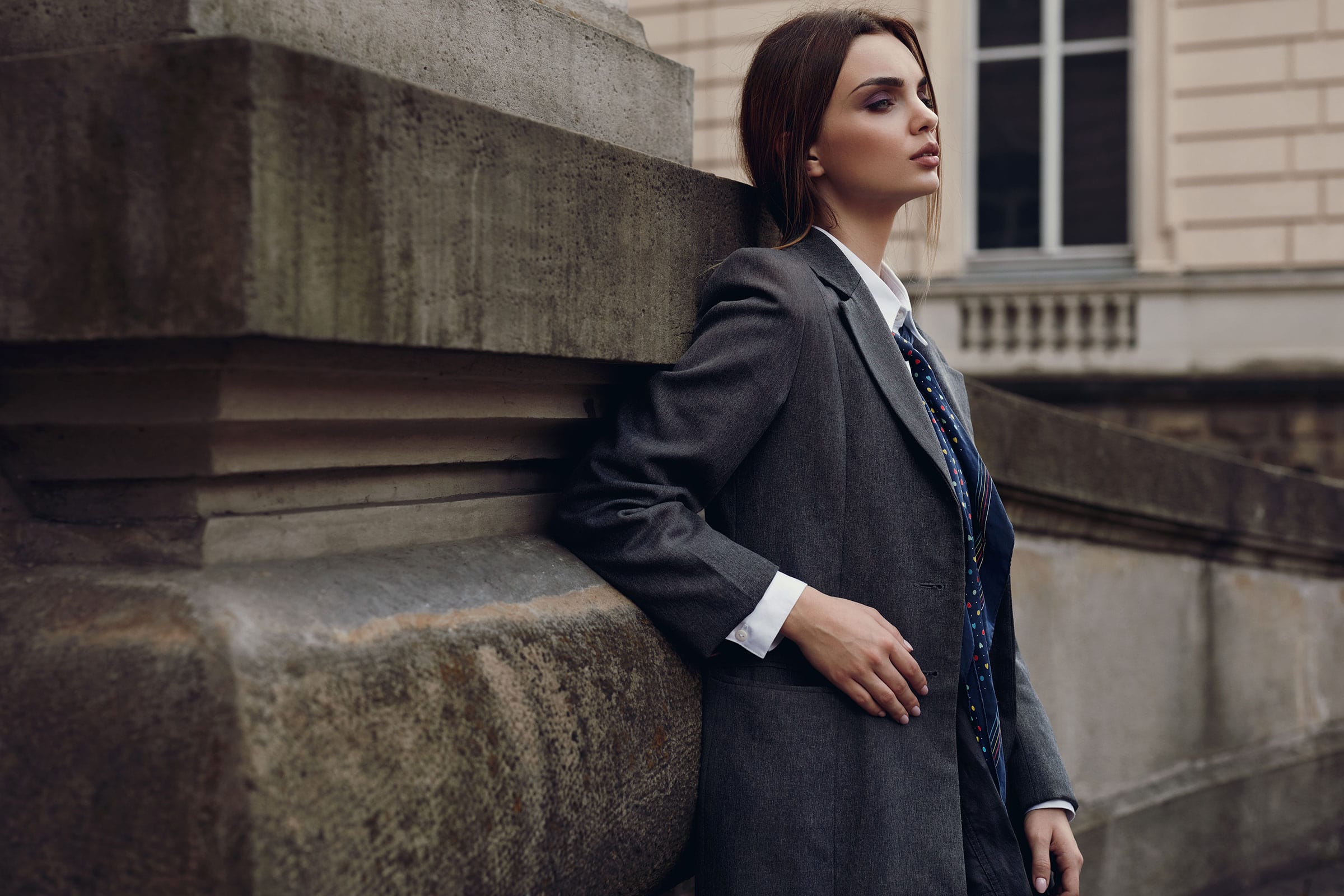 Woman in a tailored coat beside a stone building