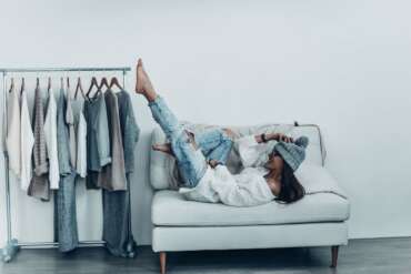 Woman relaxing beside a rail of clothes